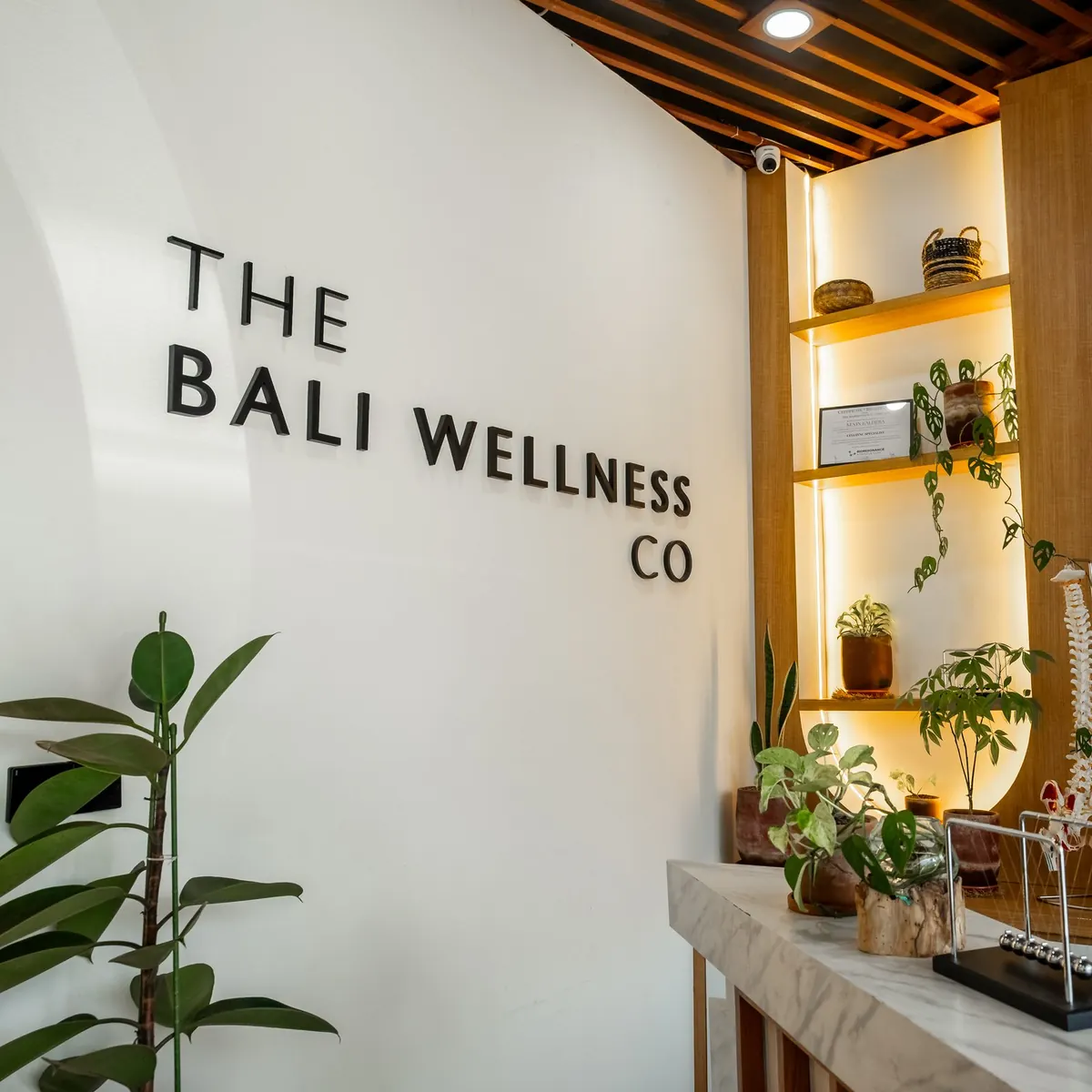 Meja resepsionis klinik di Sanur, dengan papan nama The Bali Wellness Co di atas meja marmer